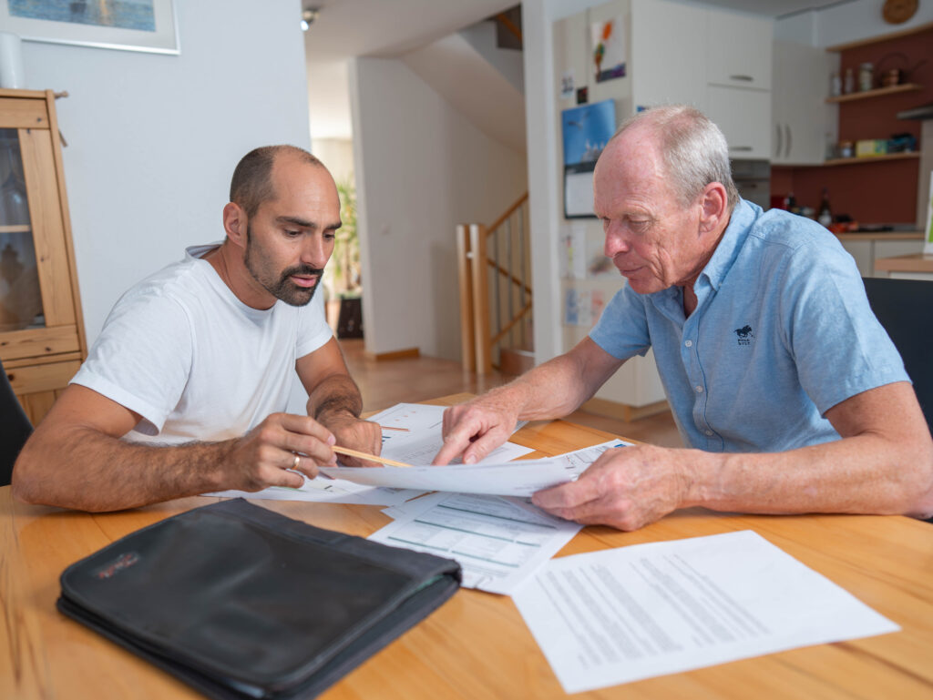 zwei Männer sitzen am Tisch und betrachten Dokumente